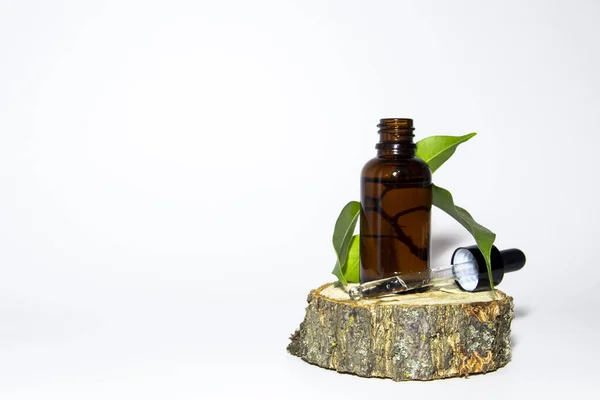 Une bouteille en verre de sérum brun avec une compte-gouttes sur un podium en bois recouvert de mousse. Concept cosmétique Spa. Place pour ton texto. Cosmétiques biologiques. — Photo
