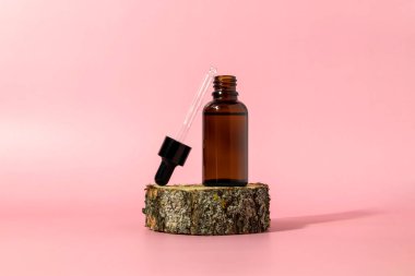 Pembe arka planda damlatan kahverengi cam şişe. Serum ya da gerekli yağ ambalajı. Kozmetik ürün Mockup.Boşluğu kopyala.