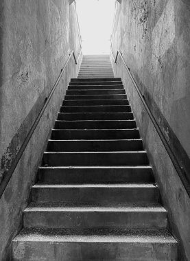 Siyah beyaz çimento tünel merdivenleri ışığa doğru ilerliyor..