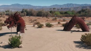 Anza Borrego Çölü 'nde koşan bir kadın. Kız ejderhanın devasa heykeline doğru yürüyor.