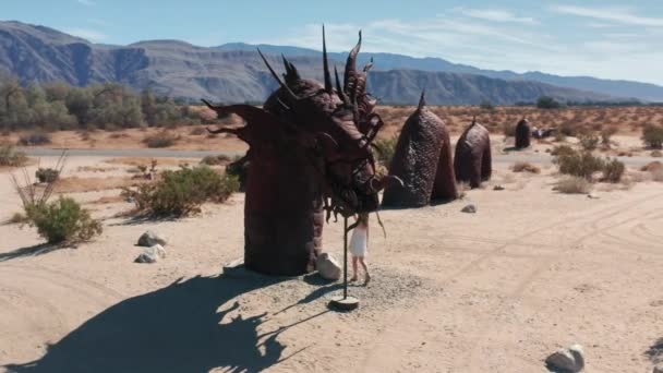 Menina tocando escultura de metal de dragão no deserto de Anza Borrego — Vídeo de Stock