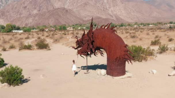 Женщина, идущая к гигантской скульптуре грагона в пустыне Анза Боррего — стоковое видео