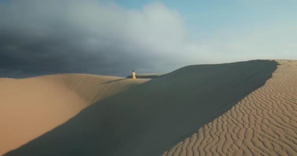 Mujer joven en vestido amarillo caminando sobre una gran duna de arena en cámara lenta — Vídeo de stock