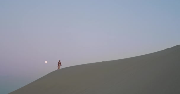 Jonge vrouw wandelen in woestijn bij zonsopgang alleen — Stockvideo