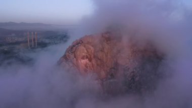 Mor bulutlar suyun üzerinde alçaktan süzülüyor, manzaralı hava manzaralı gün batımı. Mavi gökyüzü 4K