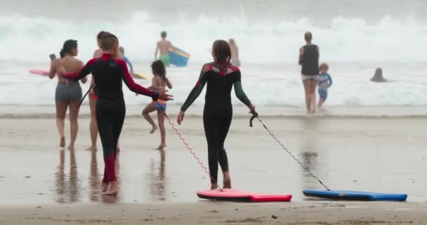 Nov. 2020. Los jóvenes surfistas usan cuerdas para llevar la tabla al océano — Vídeo de stock