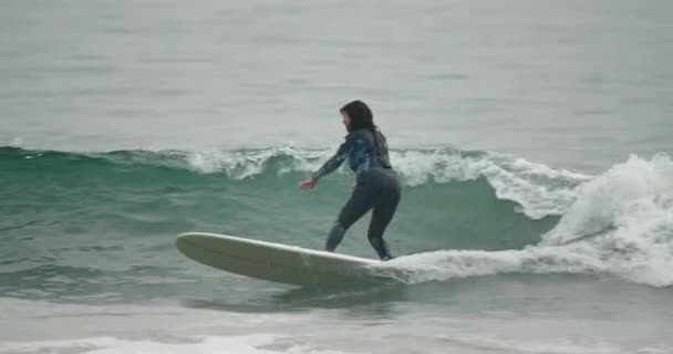 Nov. 2020. Mujer surfista monta olas en una tabla de surf blanca — Vídeos de Stock
