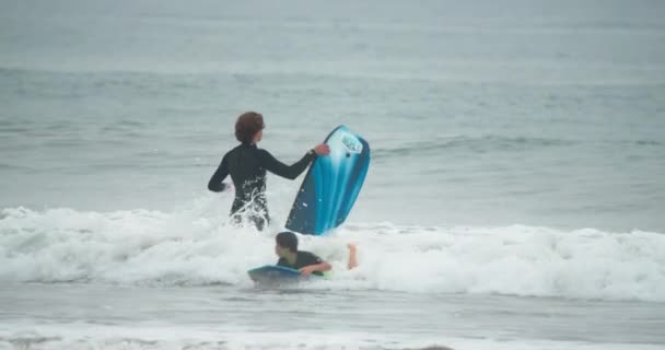 Ноябрь 2020 г. Молодой спортсмен идет к открытой воде с доской для серфинга — стоковое видео