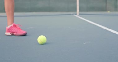 Kadın oyuncu raketle küçük topa vuruyor.