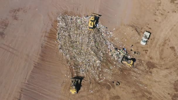 Trash trucks leveling waste polluting products. Aerial top down view of landfill — Stock Video