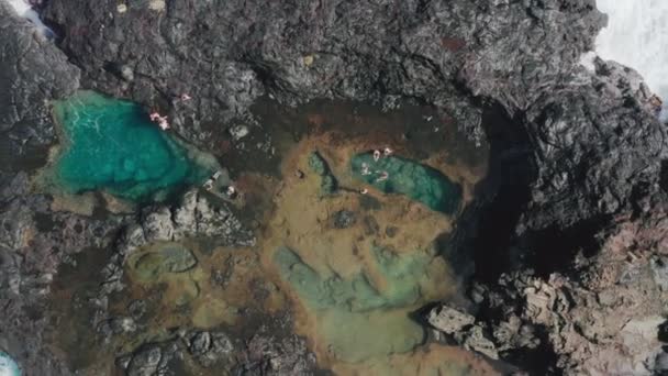 火山海岸の天然潮溜まりで泳ぐ旅行者のトップダウンビュー｜4K — ストック動画