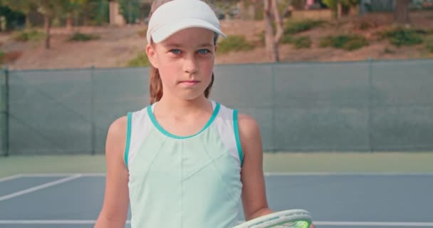 Jonge tennisser kijkt in de camera terwijl het houden van haar kleurrijke racket — Stockvideo