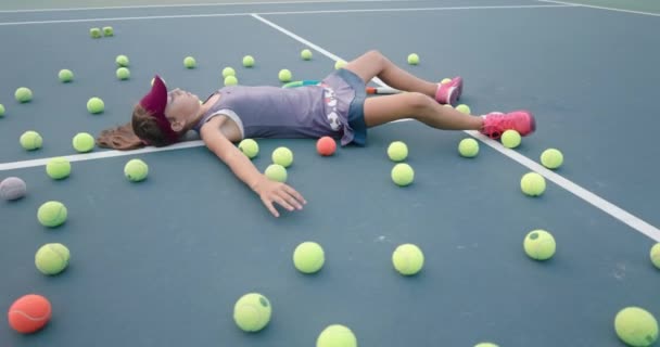 Chica haciendo ángel de nieve como ella acostada en una cancha de tenis — Vídeo de stock