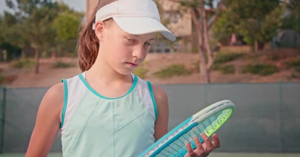 Vrouwelijke tennisspeelster herstelt haar racket en kijkt in de camera — Stockvideo