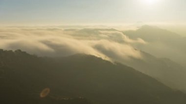 Gün batımında bulutların manzaralı dağların üzerinden geçmesi. Doğa manzarası 