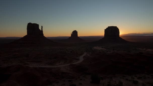 Salida del sol en Monument Valley, Airzona. Sol brillando detrás de acantilados rojos. — Vídeos de Stock