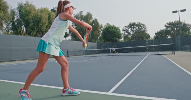 Kvinna bär blå kjol och vit topp tjänar tennisboll — Stockvideo