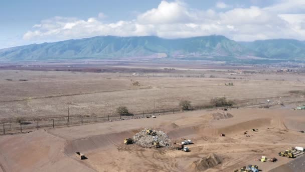 Arbeiders op stortplaats met Hawaiiaanse bergen op achtergrond, blauwe lucht en wolken — Stockvideo