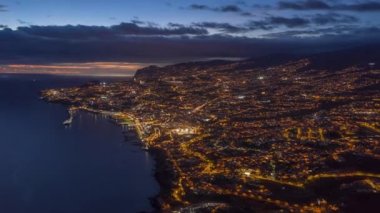 Portekiz 'in Madeira adasında geceleyin aydınlatılmış Funchal şehrinin insansız hava aracı çekimi.