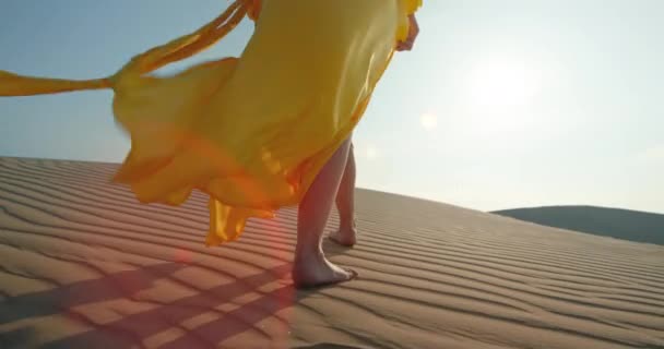 Close-up woman in yellow stylish fashion dress walking barefoot by rippled dune — Stock Video