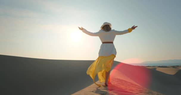 Young woman walking barefoot in desert at sunset. Pretty lady raising hands — Stock Video