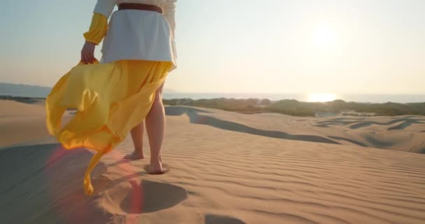 Vista posterior de la hembra caminando por arenas dunas profundas con superficie de textura ondulada. 4K — Vídeos de Stock