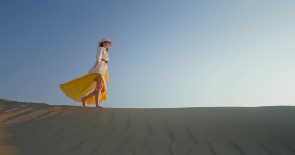 Radosna kobieta z podniesionymi rękami spacerująca po wydmie na pustyni — Wideo stockowe