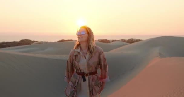 Mujer con estilo en gafas mirando alrededor del paisaje del desierto al atardecer — Vídeos de Stock