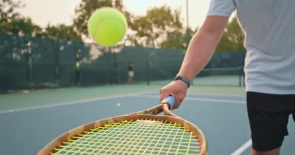 Male arm holds the racket and hits small yellow ball — Stock Video