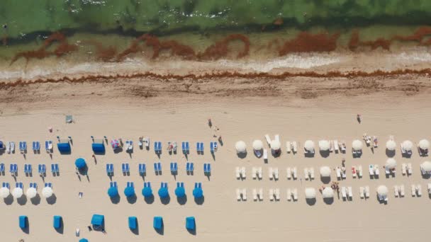 Blick über den weißen Sandstrand am Meer und Menschen, die sich im Resort-Hotel entspannen — Stockvideo