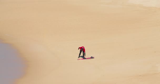 Nazare，葡萄牙。October 2020.身穿五颜六色泳衣的人拿着他的板 — 图库视频影像