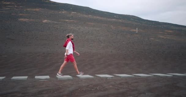 Νησί Faial, Πορτογαλία. Ο άνθρωπος περπατά κατά μήκος ηφαιστειακού εδάφους φορώντας πολύχρωμα ρούχα — Αρχείο Βίντεο