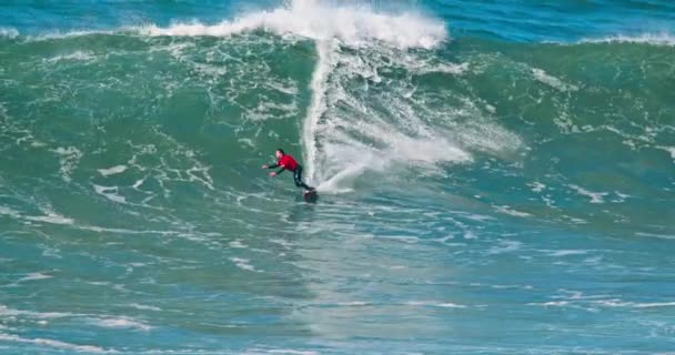 Nazare, Portugalia. Październik 2020. Mężczyzna w czerwonym stroju kąpielowym surfing na Oceanie Atlantyckim — Wideo stockowe