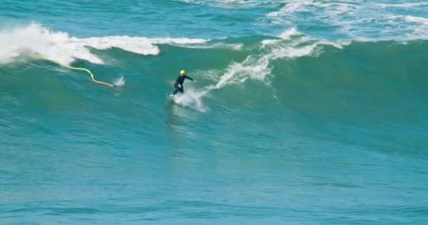 Nazare, Portugal. Outubro de 2020. Esportista masculino monta uma onda segurando uma corda — Vídeo de Stock