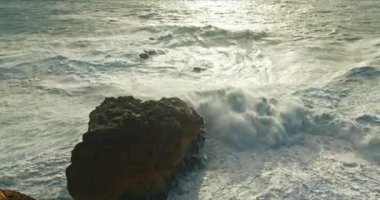 Portekiz 'in altın saatinde Nazare kıyılarında dalgalar kopan Rocky plajı.