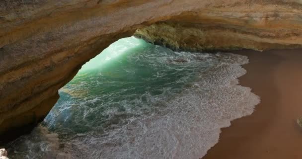 A large hole inside of a rocky cliff covered with foamy tide seen from the top — Stock Video