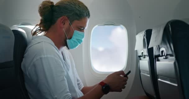 Uomo caucasico in maschera medica legge sul suo telefono — Video Stock