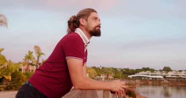 Vue latérale d'un homme caucasien appuyé sur les balustrades d'un pont — Video