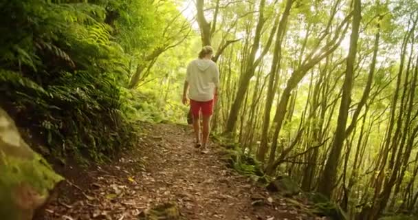 Man i röda shorts promenera längs en stig i tjock skog — Stockvideo