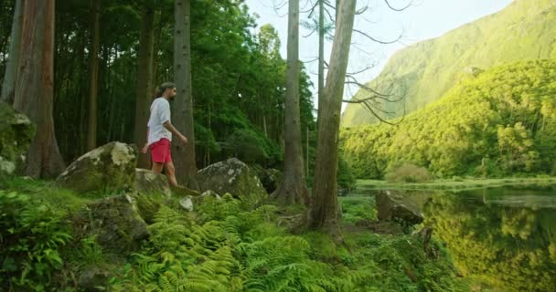 Caucasian man enjoys beautiful panoramic view of the lake surrounded with plants — Wideo stockowe