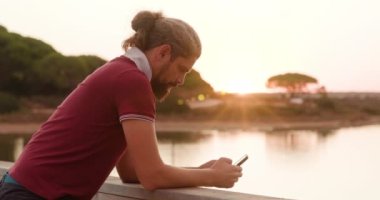 Gölün kıyısındaki köprüde aletini kullanan bir adamın yan görüntüsü.