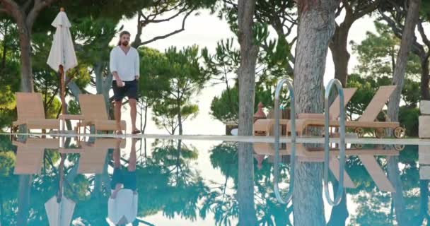 Homme se promène le long d'une piscine dans une station balnéaire isolée — Video