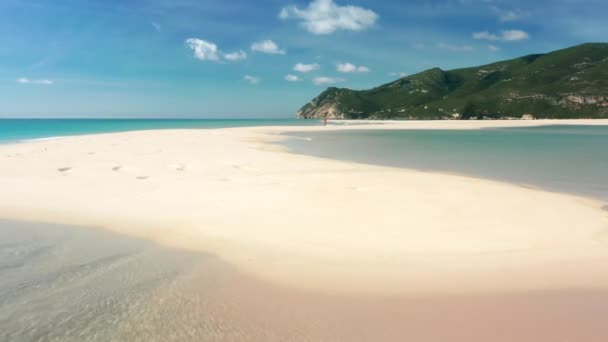 A man walking along sandy beach with a magnificent cliff in the background — Αρχείο Βίντεο