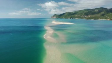 Crystal clear waters surrounds cliffs covered with lush green vegetation