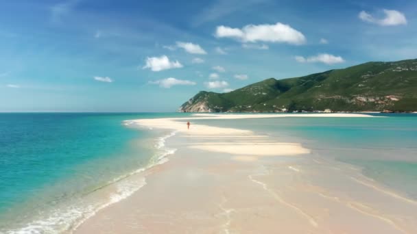 Aerial view of a man running across a narrow sandy path within the sea — Vídeo de stock