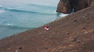Man looking ocean waves rolling on volcanic beach of Faial Island, Azores