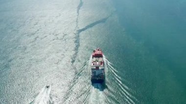 Bir kargo gemisi konteynerleri açık okyanus sularına doğru taşıyor.