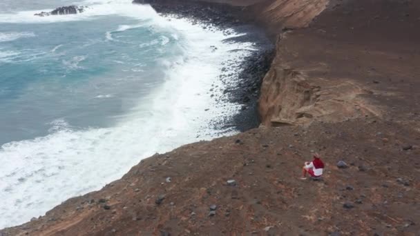 Homem sentado na rocha e a olhar para as ondas do oceano na Ilha do Faial, Açores, Portugal — Vídeo de Stock