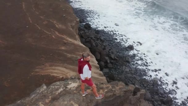 해변가에 바다로 둘러싸인 한 관광객이서 있다 — 비디오