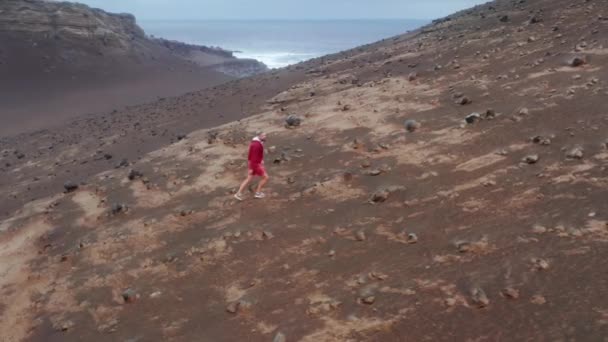 화산을 거닐고 있는 한 남자의 공중 촬영 장면 — 비디오